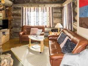 A cozy log cabin interior with two leather sofas, a wooden coffee table, a television, and a radio. - Luostonseita 1 by Interhome (Sodankylä)