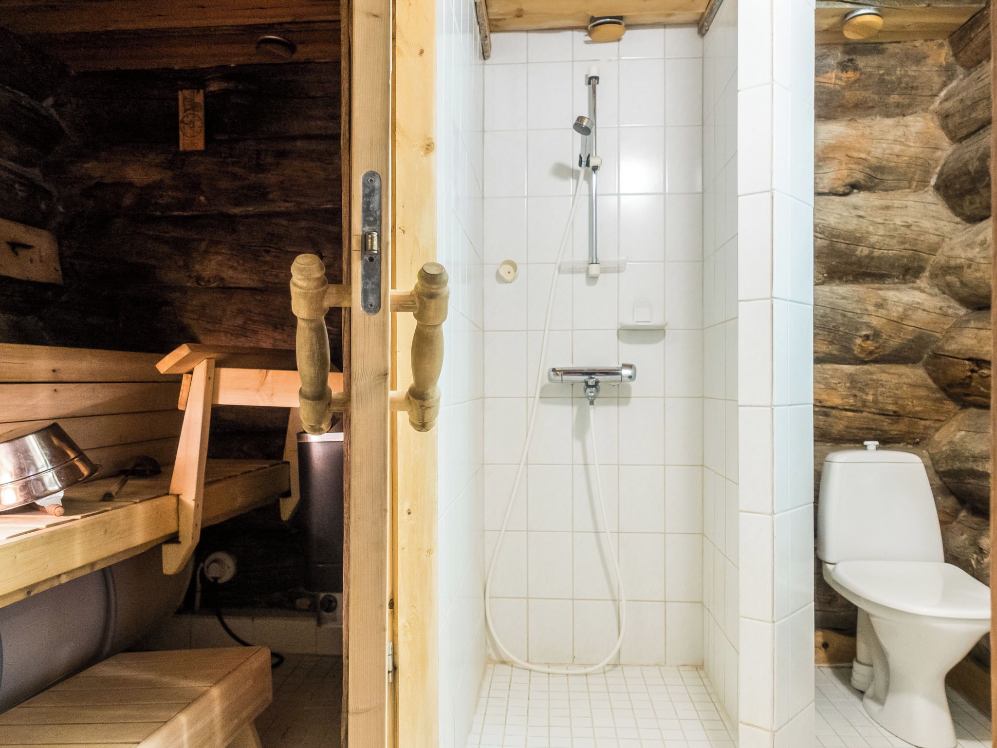 A bathroom with a wooden door, a shower, and a toilet.