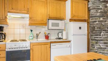 A kitchen with wooden cabinets, a microwave, a refrigerator, a stove, and a dishwasher.