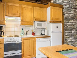 Une cuisine équipée d’armoires en bois, d’un four à micro-ondes, d’un réfrigérateur, d’une cuisinière et d’un lave-vaisselle.