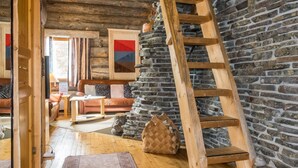 Een rustiek interieur met een stenen muur, een houten ladder en een gezellige zithoek met een bank en salontafel.