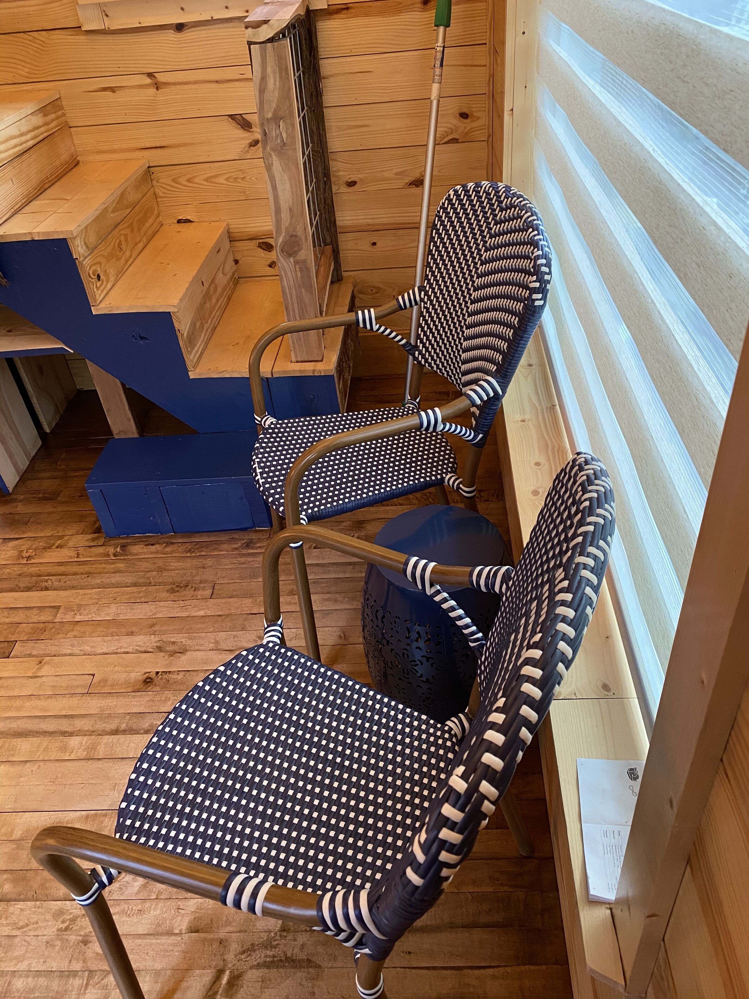 A wooden interior with two chairs with black and white patterned upholstery, a wooden bench, and a wooden wall with horizontal planks.