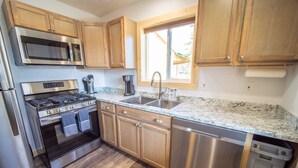 A modern kitchen with stainless steel appliances, wooden cabinets, and a granite countertop.