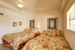 Une chambre avec deux lits, un luminaire au plafond et des œuvres d’art encadrées accrochées aux murs.