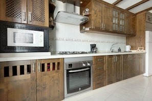 A kitchen with wooden cabinets, a microwave, an oven, and a coffee maker.