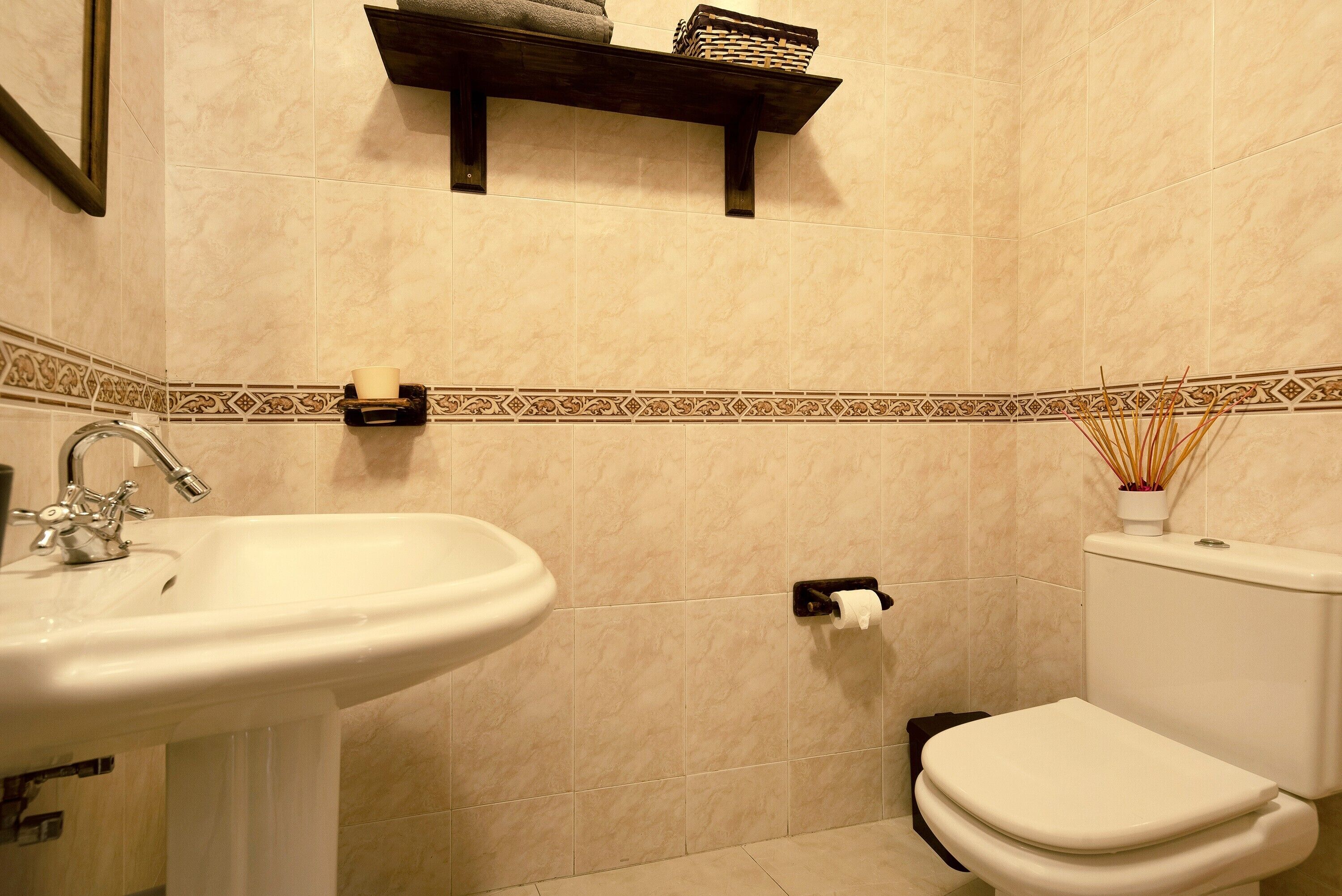 A bathroom with a sink, toilet, and shelf with toiletries.