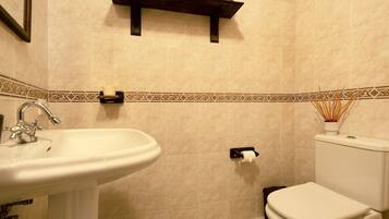 A bathroom with a sink, toilet, and shelf with toiletries.