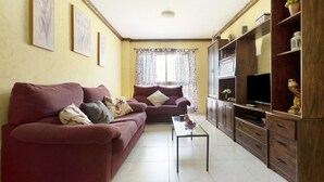 A living room with two sofas, a coffee table, a TV, and wooden cabinets. - Vacation Home "Apartamento Vistas de Icod" with Mountain View, Sea View & WiFi (Icod de los Vinos)