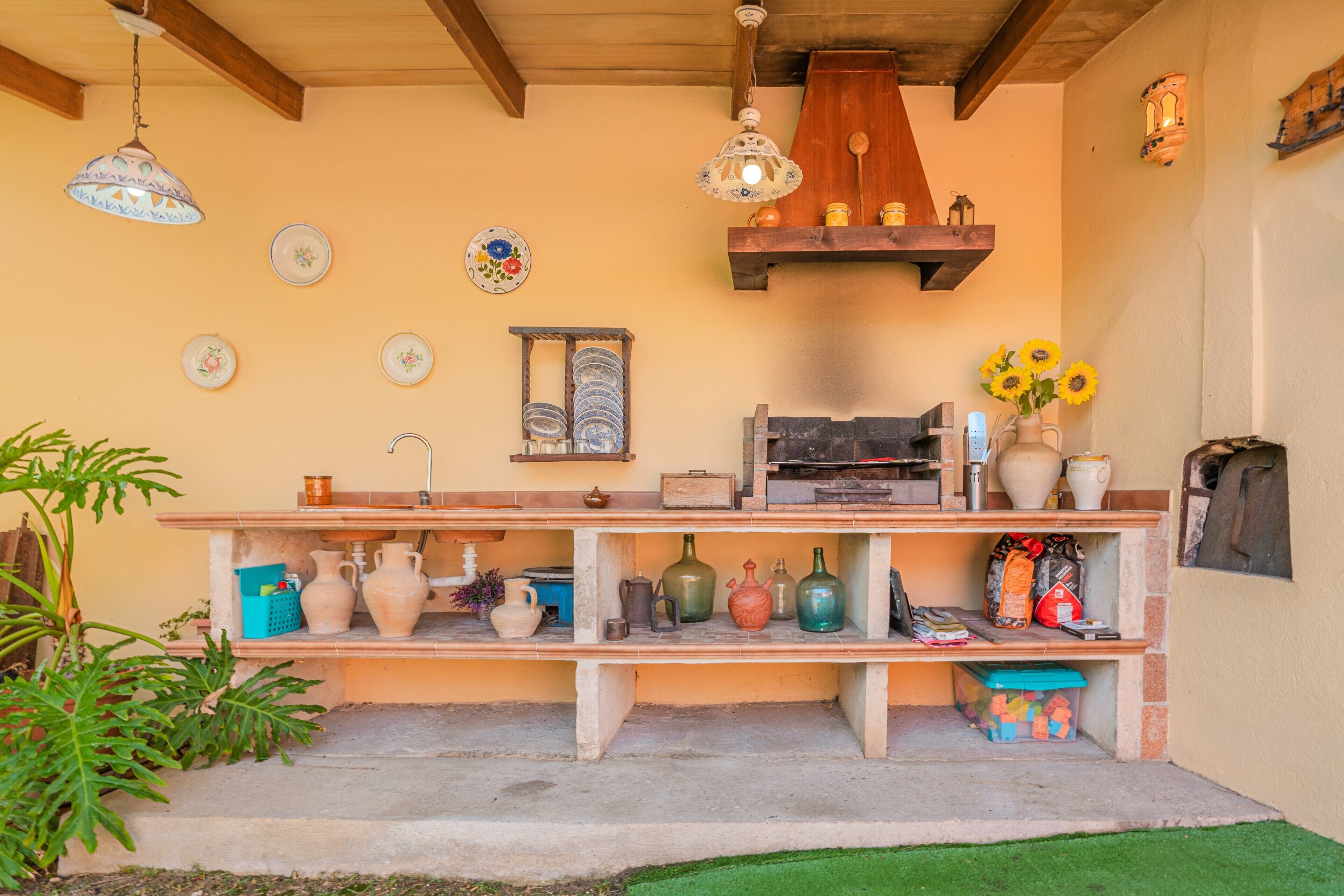 A kitchen with shelves holding various kitchenware, a hanging light fixture, and a wall-mounted shelf with decorative items.