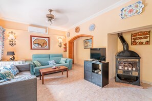 Una sala de estar con sofá, mesa de centro, televisión, chimenea y elementos decorativos en la pared.