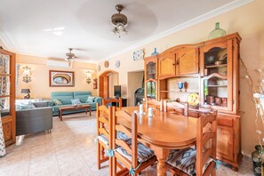 Un comedor con mesa y sillas de madera, un sofá y un aparador con vajilla.
