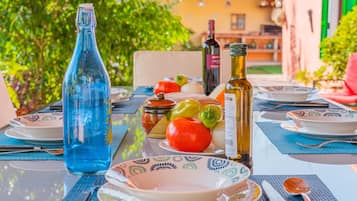 A table set with plates, a bottle, and a bowl of fruit.