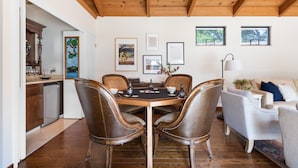 Un comedor con mesa de madera y sillas de cuero, un sofá blanco y cuadros en la pared.