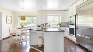 Una cocina moderna con armarios blancos, un refrigerador de acero inoxidable grande y una isla central con un florero.