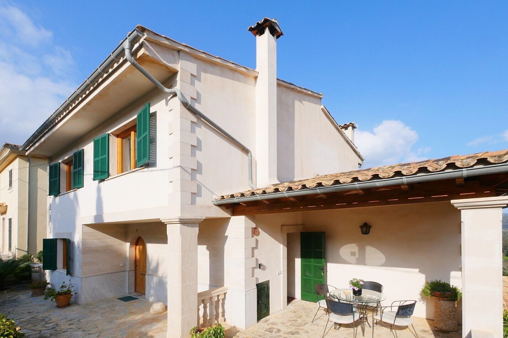 A traditional building with a stone-paved courtyard, a wooden door, and a small outdoor seating area with chairs and a table.