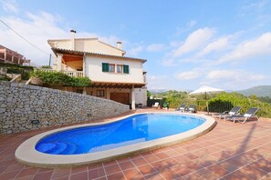 Une villa avec piscine, un mur en pierre et une vue sur les montagnes.