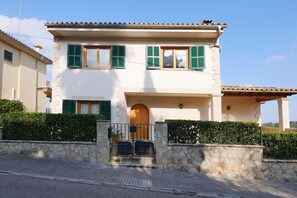 Un bâtiment à deux étages, doté d’une façade en pierre, de volets verts et d’une porte en bois.