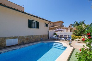 A swimming pool with lounge chairs, a stone wall, and a building with a tiled roof. - Vacation Home Villa Loli with Mountain View, Wi-Fi, Pool, Terrace & Balcony (Alcudia)