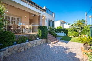 A residential building with a covered patio, outdoor furniture, and a stone staircase leading to a second floor. - Vacation Home Villa Loli with Mountain View, Wi-Fi, Pool, Terrace & Balcony (Alcudia)