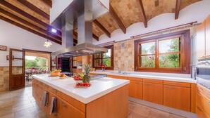 Cozinha moderna com uma ilha grande, armários de madeira e vista para o exterior.