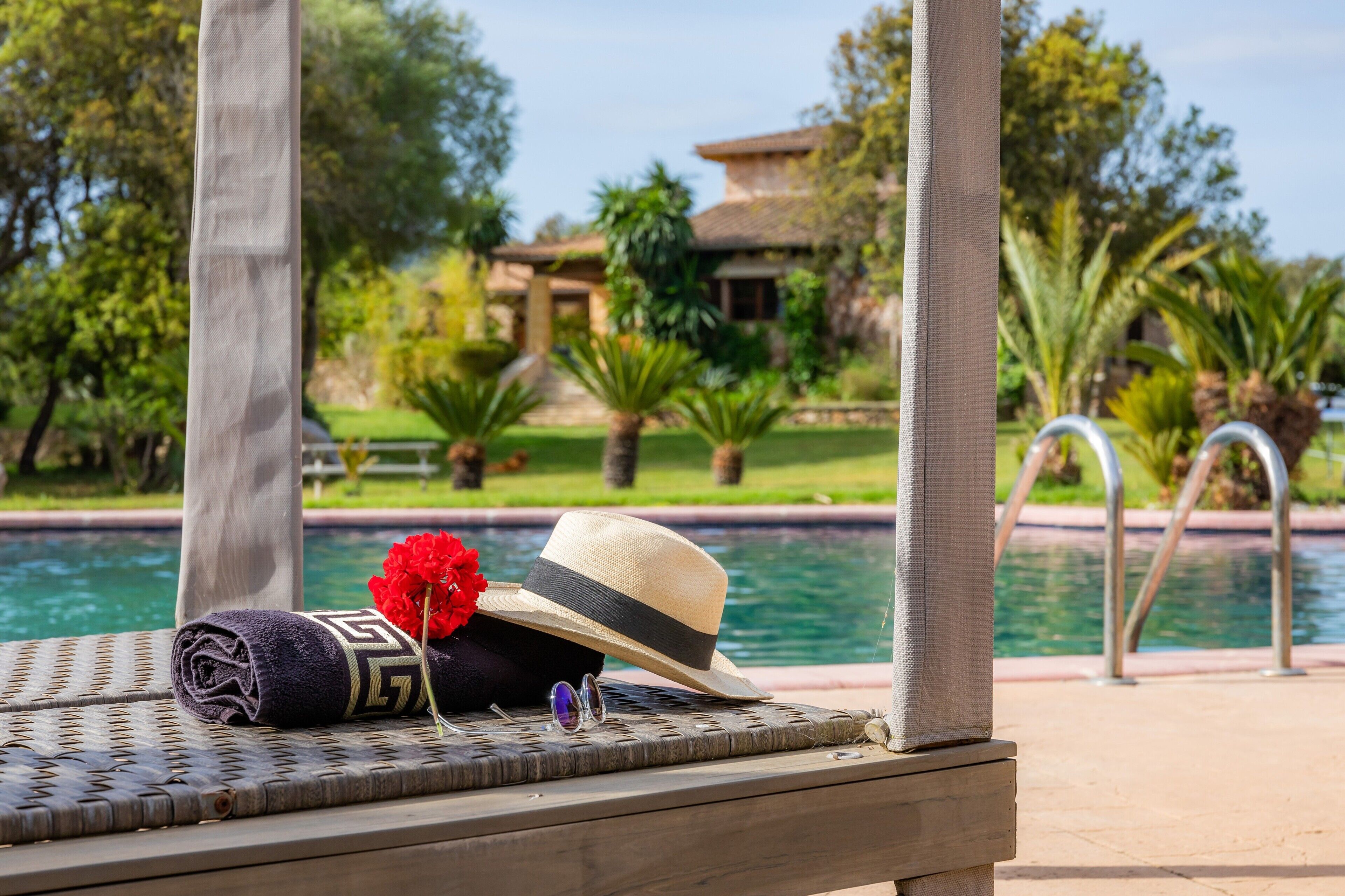 Un área de descanso junto a la piscina con un sombrero, gafas de sol y una toalla.