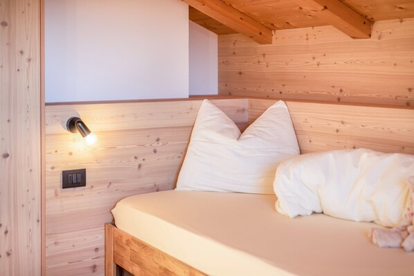 Een houten kamer in chaletstijl met een bed, kussens en een wandlamp.