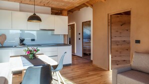 Une cuisine moderne avec des meubles blancs, un plafond en bois et un coin repas comprenant une table et des chaises.