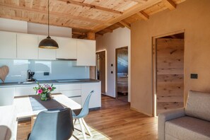 Eine moderne Küche mit weißen Schränken, einer Holzbalkendecke und einem Essbereich mit Tisch und Stühlen.