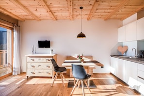 Eine moderne Küche mit Holzbalken, einem Esstisch mit Stühlen, einem Fernseher und einem Waschbecken.