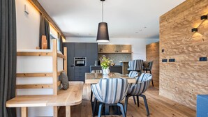 Eine moderne Küche mit Einbauofen und Essbereich, ausgestattet mit gestreiften Stühlen und einem Holztisch.