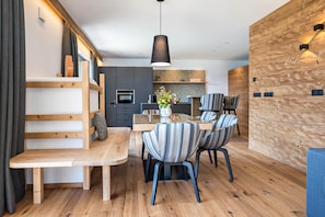 A modern kitchen with a built-in oven and a dining area with striped chairs and a wooden table.