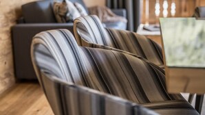 Ein modernes Wohnzimmer mit einer Couch und gestreiften Sesseln, Holzboden und einem Laptop auf einem Tisch.