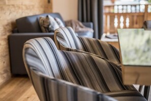 Moderni olohuone, jossa on sohva ja raidalliset nojatuolit, puulattia ja pöydällä kannettava tietokone.