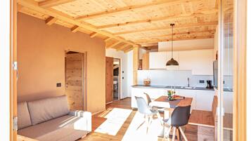 Un interior moderno con techo de madera, un sofá, una mesa de comedor con sillas y una zona de cocina.