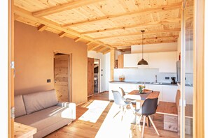 A modern interior with a wooden ceiling, a sofa, a dining table with chairs, and a kitchen area.