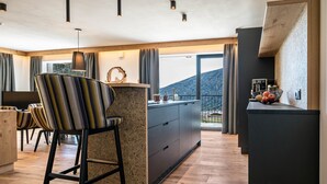 Una cocina moderna con una isla central, taburetes de bar y vistas al exterior.