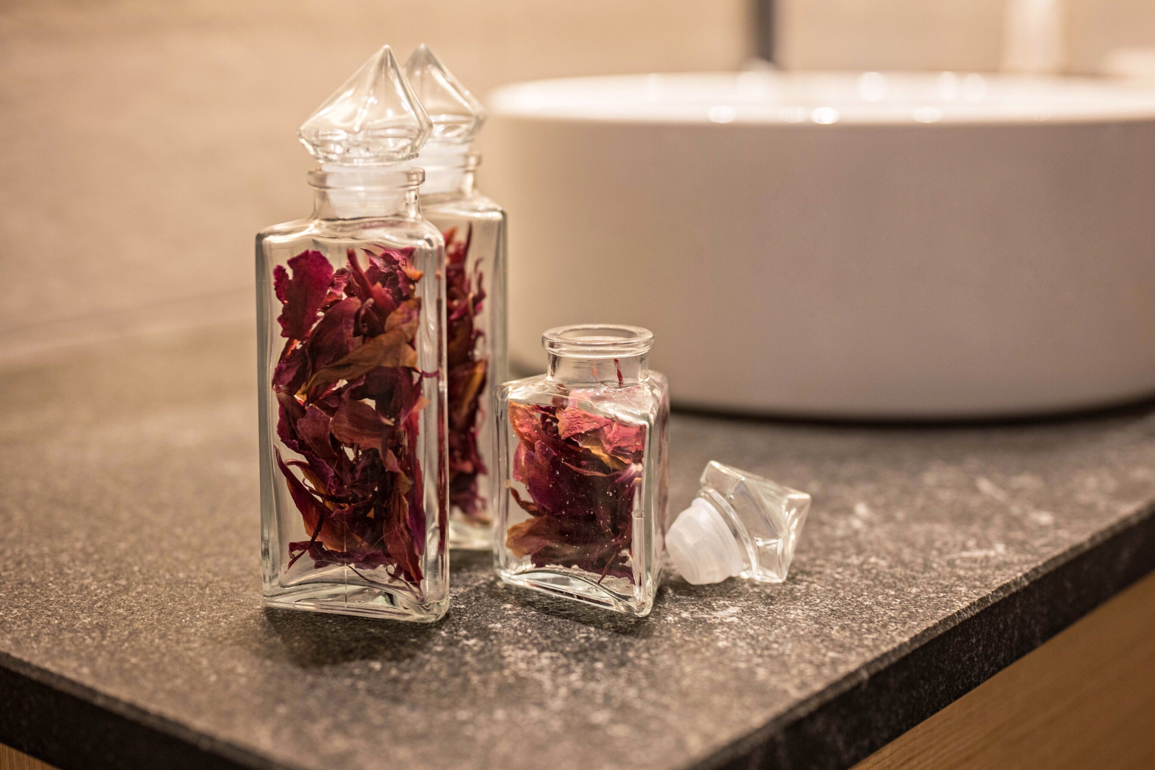 Trois bouteilles en verre contenant des fleurs séchées, posées sur un comptoir.
