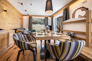 Zona pranzo moderna con tavolo in legno, sedie a righe e vista sull'esterno.