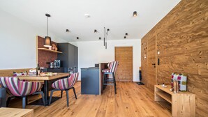 Eine moderne Küche mit Holdekor, ein Essbereich mit gestreiften Stühlen und einer Wand aus Holz.
