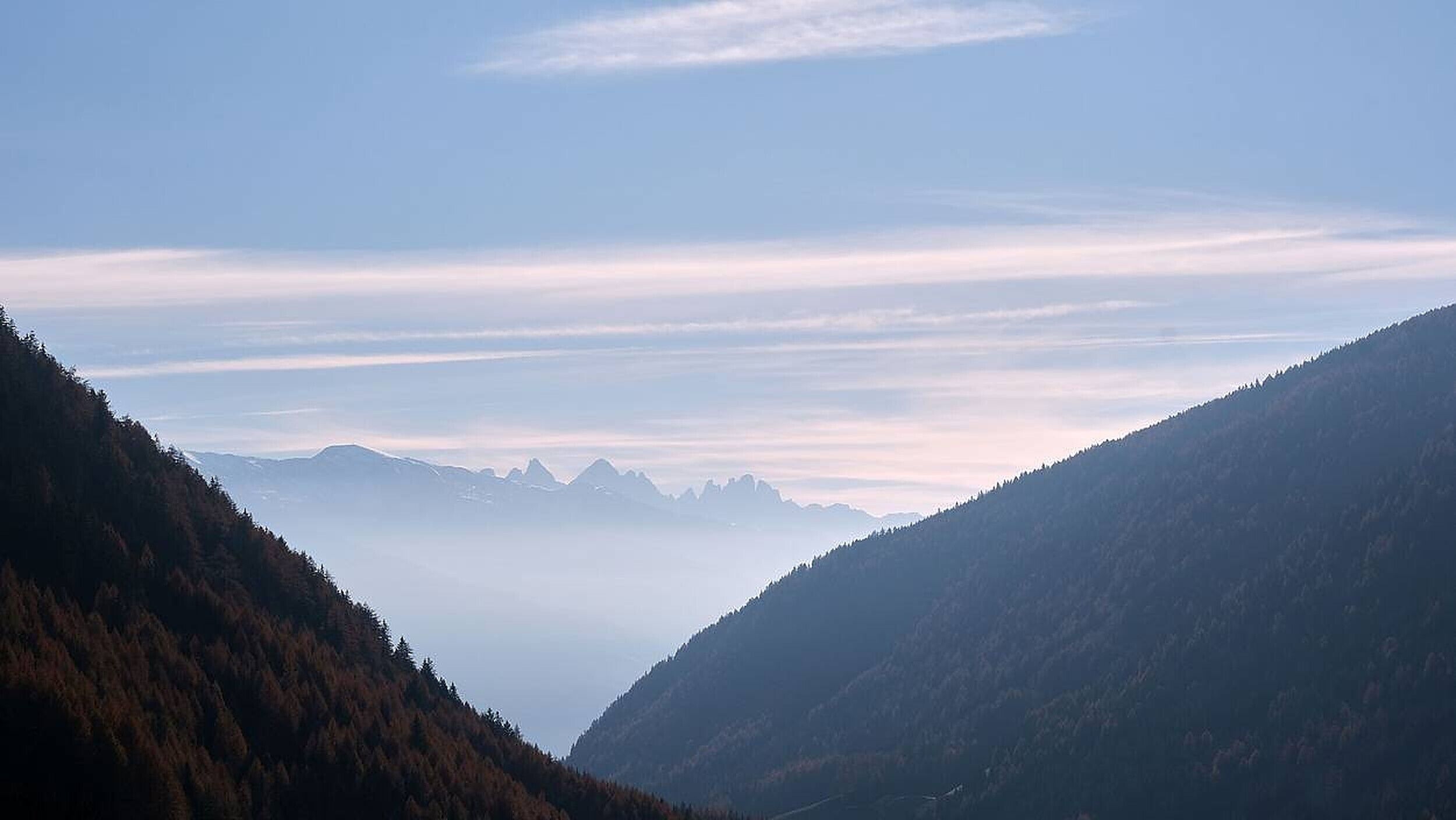 A mountainous landscape with a valley and distant peaks.