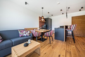 Un espacio moderno para vivir con sofá, mesa de comedor, sillas y una pequeña cocina.