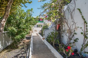 A narrow alleyway with a gravel path, surrounded by greenery and white walls. - Apartamento Sol y Playa with Pool, Wi-Fi, Terrace & Garden (Puerto del Carmen)