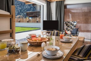 A breakfast table with various food items, a television, and a view of a mountainous landscape.