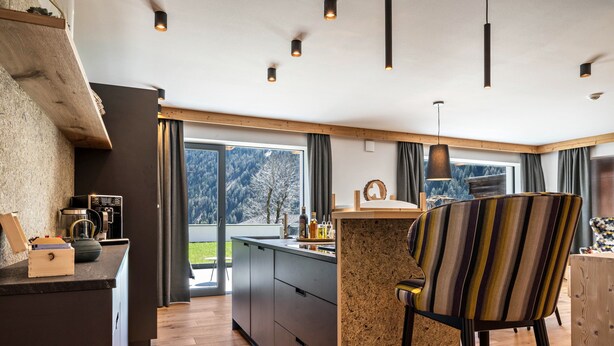 A modern kitchen with a large island, wooden accents, and a view of a snowy landscape. - Apartment "Mulin Hilda" next to the Skiing Area with Mountain View, Sauna & Garden (Vals)