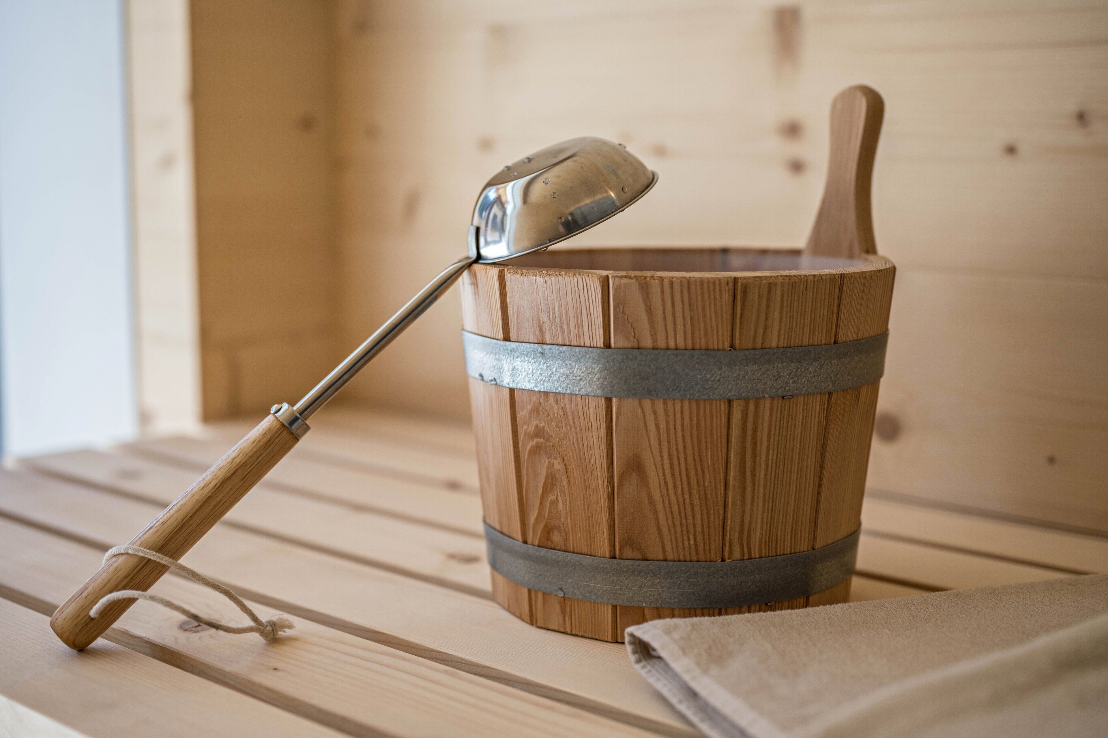 Una sauna in legno con una mestola e un catino di legno.