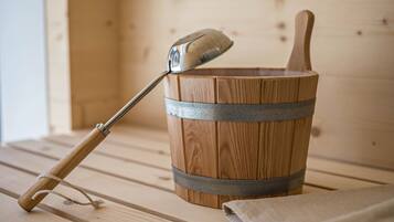Una sauna in legno con una mestola e un catino di legno.