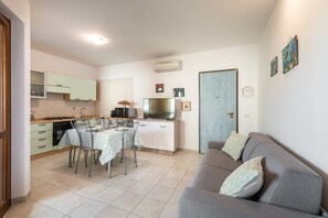A compact living space with a kitchen, dining area, and a sofa. - Apartment 'Isabel' with Shared Pool, Wi-Fi and Air Conditioning (villasimius)