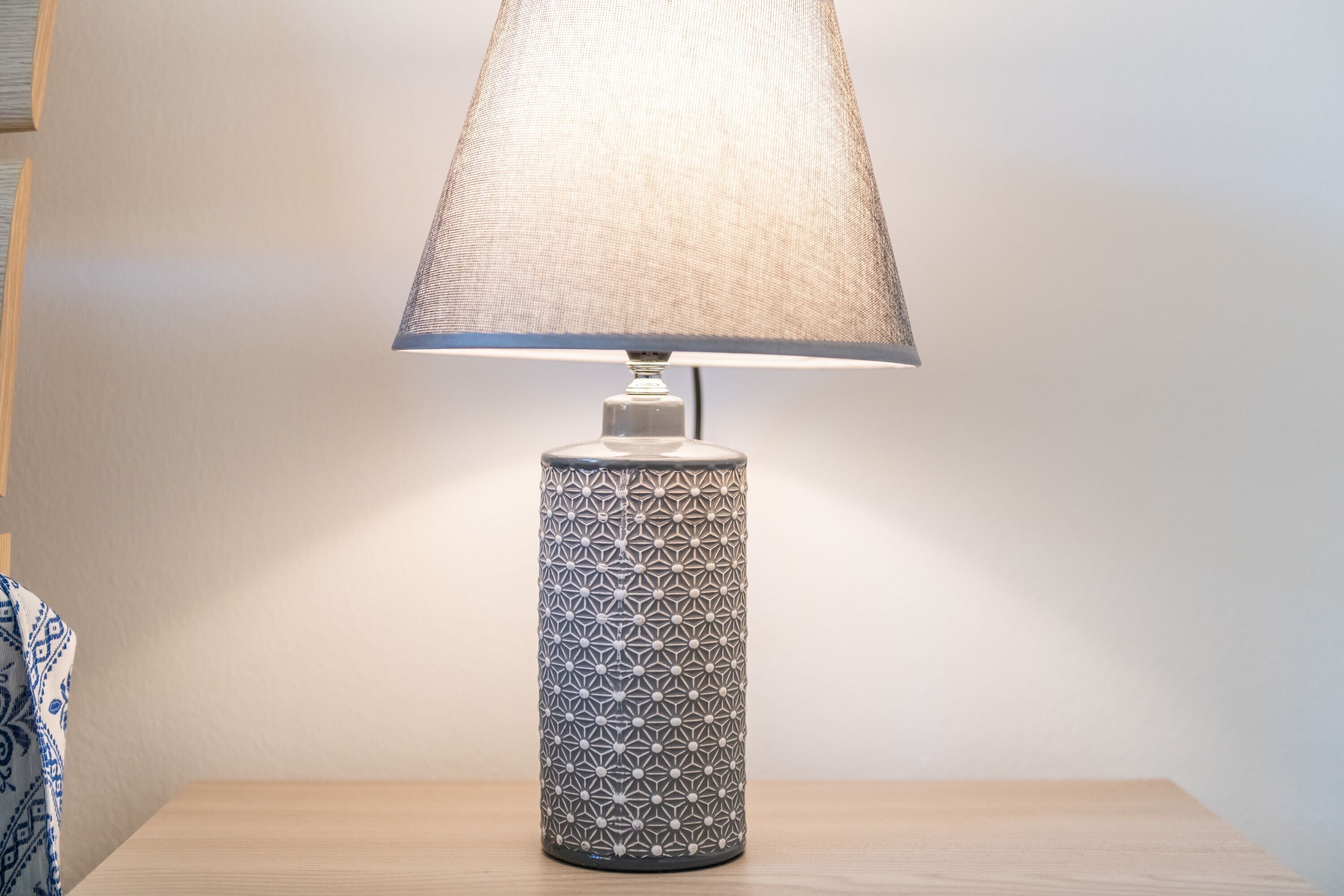 A table lamp with a geometric pattern on its base, placed on a wooden surface.