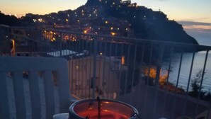 Een kaars op een balkon met uitzicht op een kustplaats bij zonsondergang.