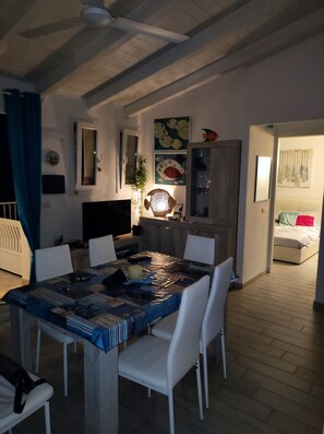 A dining area with a table covered in a blue tablecloth, white chairs, and a ceiling fan. - Attico Meraviglioso sul Mare, Appartamento con Ampio Terrazzo Vista 180 Gradi (Castelsardo)